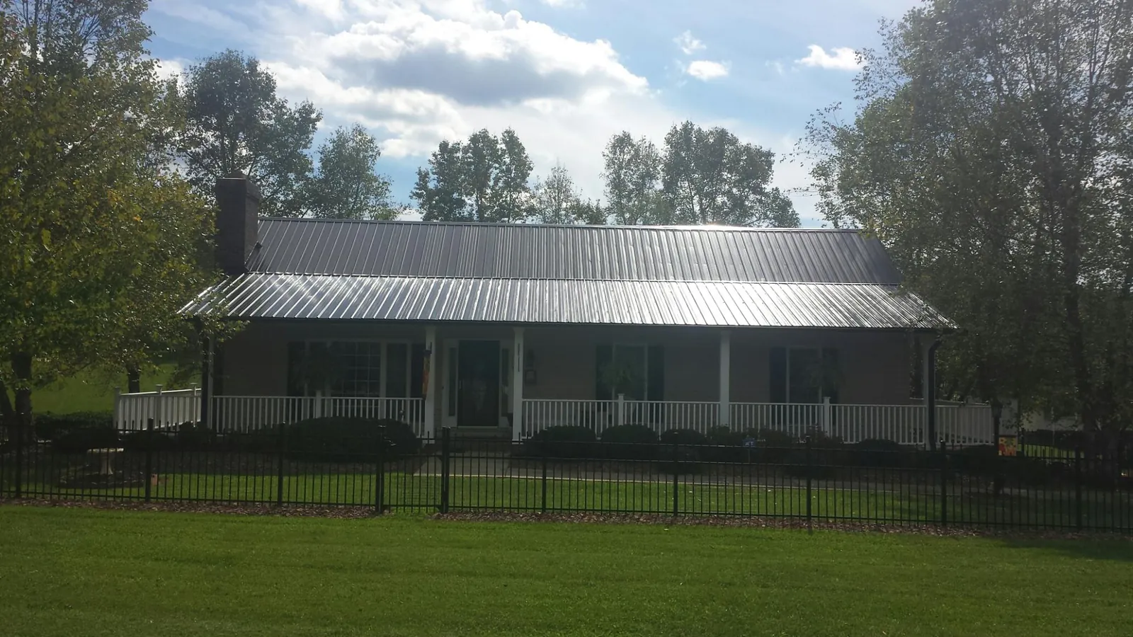 Gray metal roof on a brick ranch with a full width front porch — Gutter Guard Installation work by our crew in Maxwell